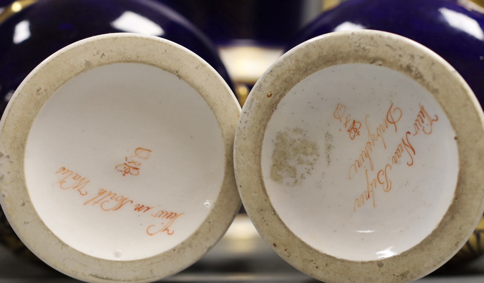 A garniture of three Derby named twin handled cups, View near Belper, Derbyshire, and 'View in North Wales' and 'View near Rome', 17cm and 20.5cm
